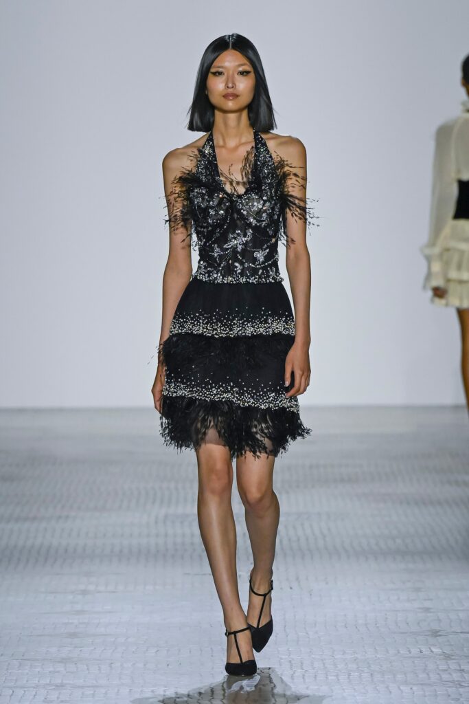 A fitted black silk sleeveless dress with a V-neckline and tiered fringed detailing.