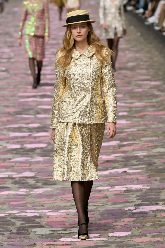 A fitted gold silk suit with long sleeves and a collared neckline, featuring a structured pencil silhouette.