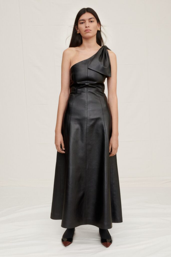 A fitted black leather sleeveless dress featuring a V-neckline and A-line silhouette.