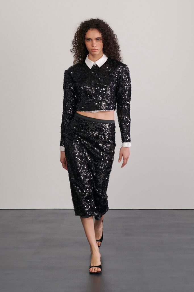 A fitted black sequin long-sleeve top with a collared design paired with a pencil skirt.