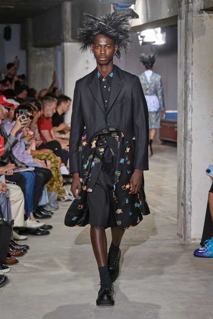 A relaxed black coat dress with long sleeves and a collared neckline featuring a printed design.