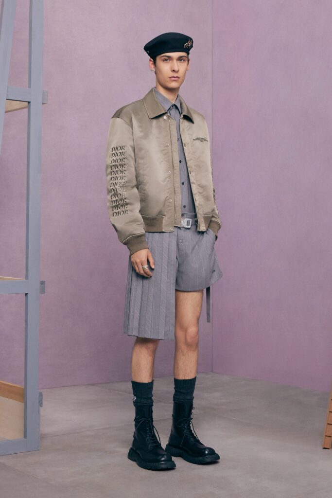 An oversized beige jacket paired with pleated gray shorts for a stylish, contemporary look.