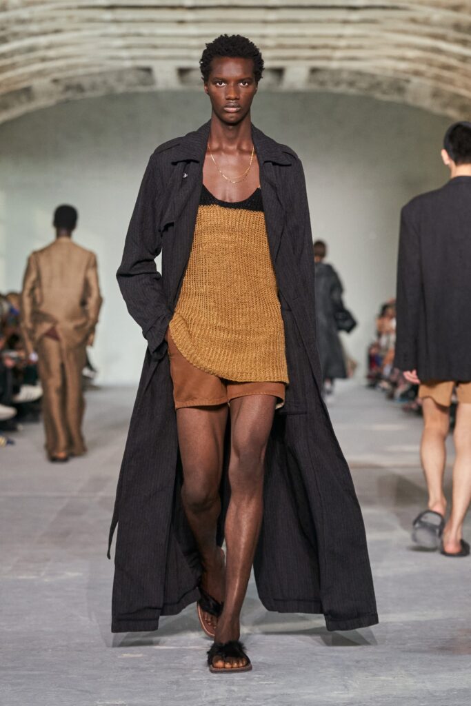 A relaxed black coat layered over a brown v-neck top, perfect for a stylish look.