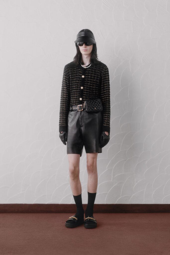 A fitted black leather long-sleeve jacket with a collared design paired with matching shorts.