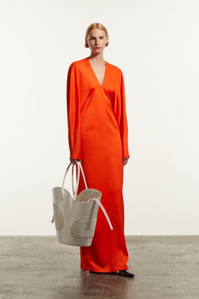 A fitted orange silk dress with long sleeves and a V-neckline.