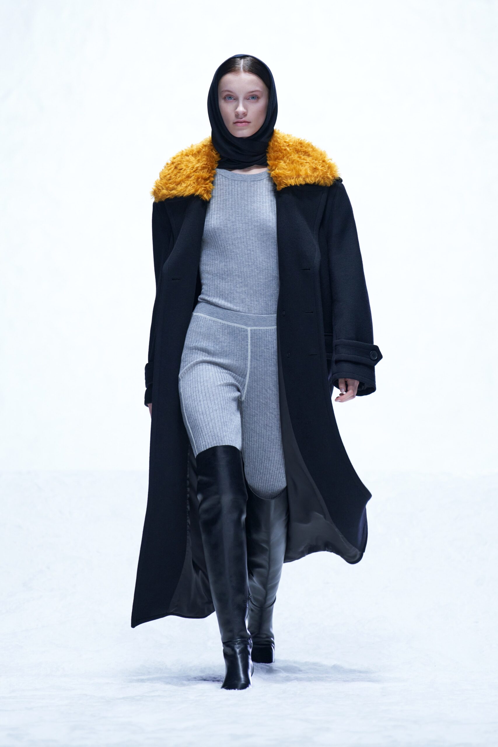 A fitted black wool coat with an orange collar layered over a gray dress.