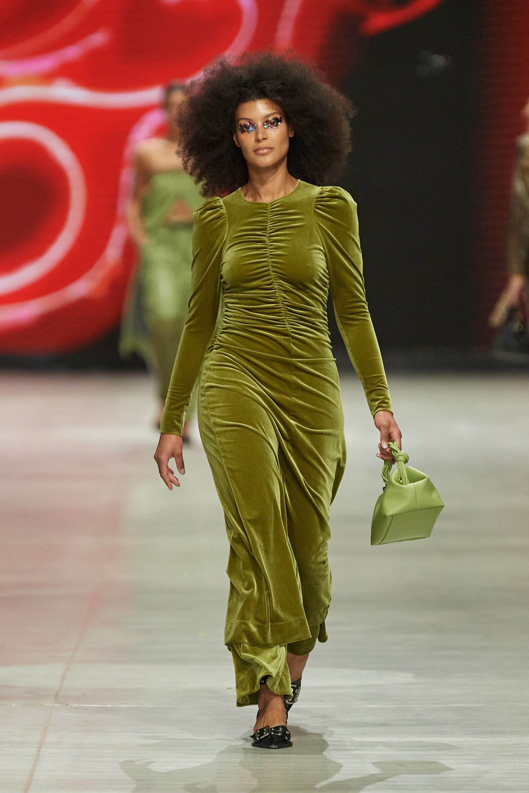 A fitted green velvet dress with long sleeves, a V-neckline, and ruched detailing.