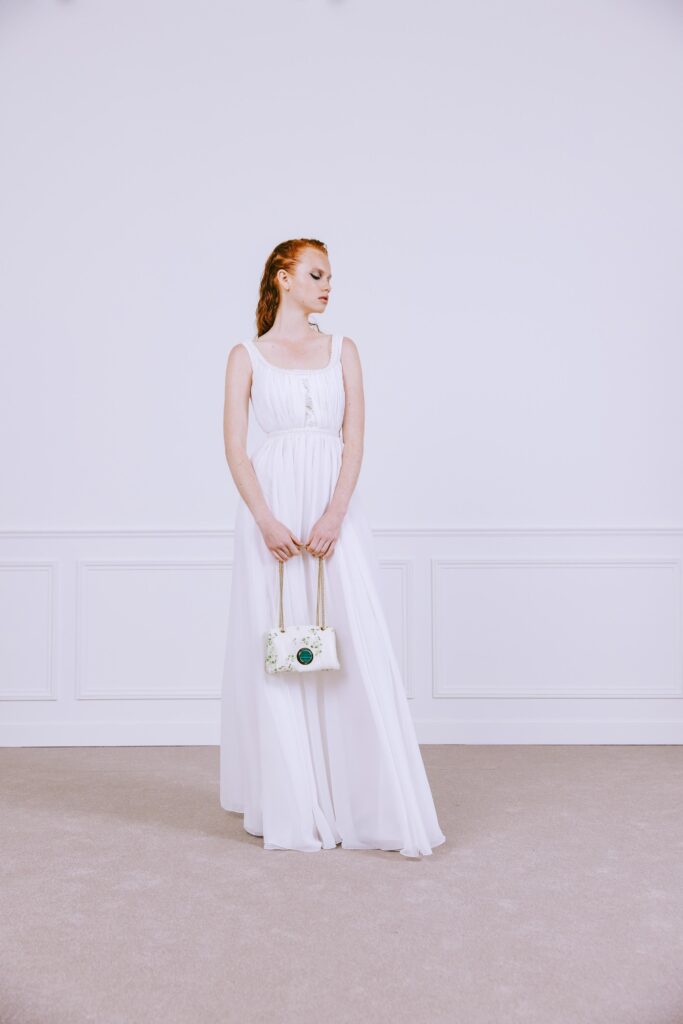 A fitted white silk sleeveless maxi-dress with a tiered design and collared neckline.
