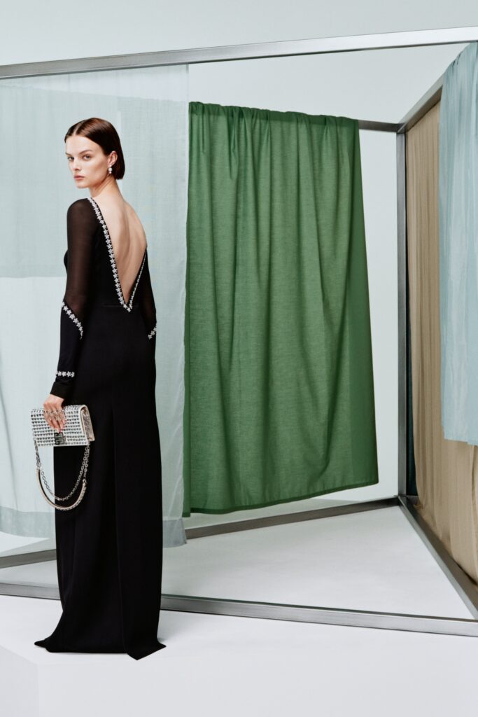 A fitted black silk dress with long sleeves and a backless design featuring a slit.