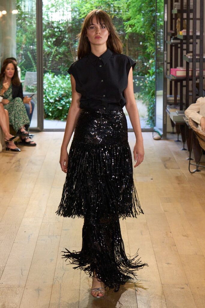 A fitted black sequined top with short sleeves paired with a fringed black skirt.