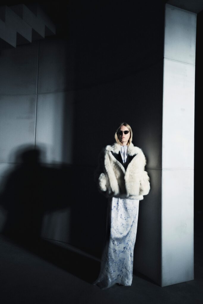 A fitted white printed maxi dress paired with a luxurious fur coat.