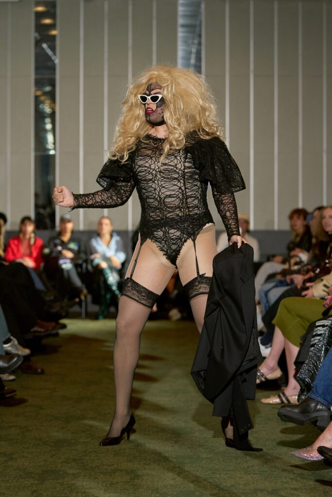 A fitted black lace bodysuit with a V-neckline, complemented by a stylish coat.