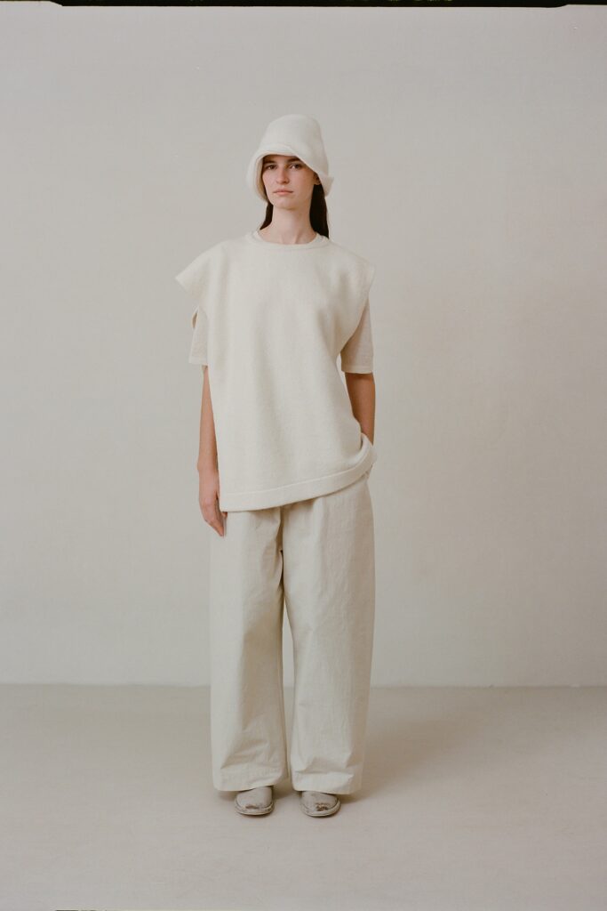 A relaxed white short-sleeve top with asymmetric design paired with loose-fitting pants.