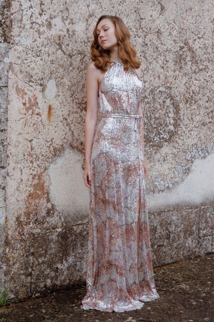 A fitted silver sequin gown with a sleeveless halter design and a maxi silhouette.