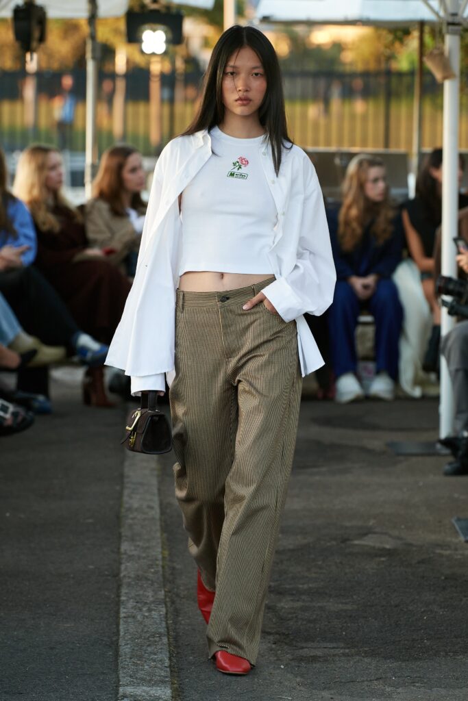 A relaxed white long-sleeve cropped top paired with beige striped pants.