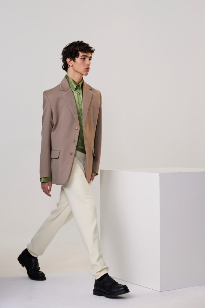 A tailored beige blazer paired with green collared shirt and cream pants.
