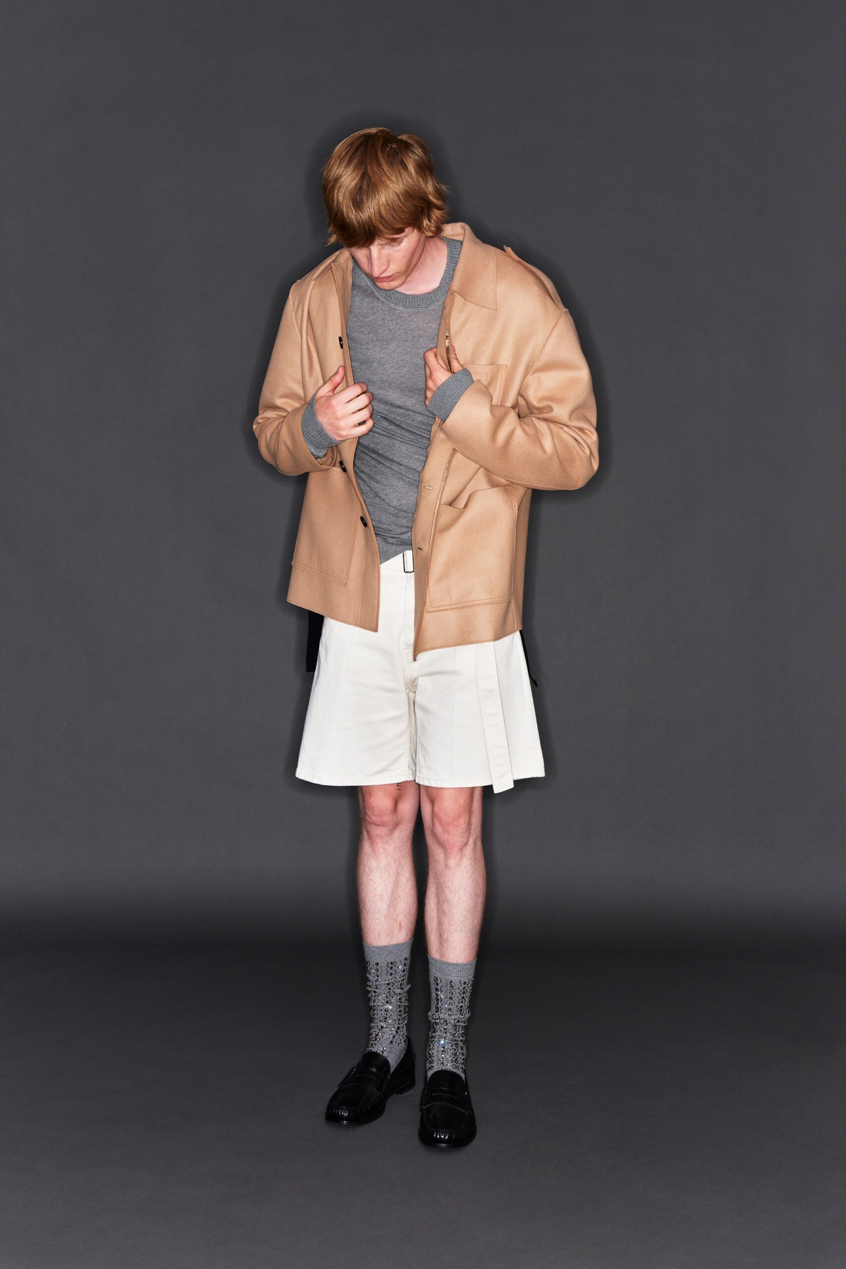 A relaxed beige jacket paired with pleated white shorts for a stylish look.