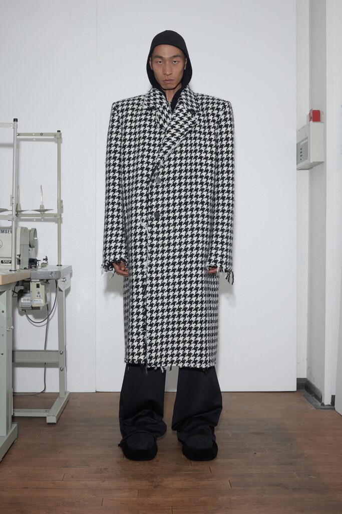 An oversized black and white checked coat with long sleeves and a collared design.