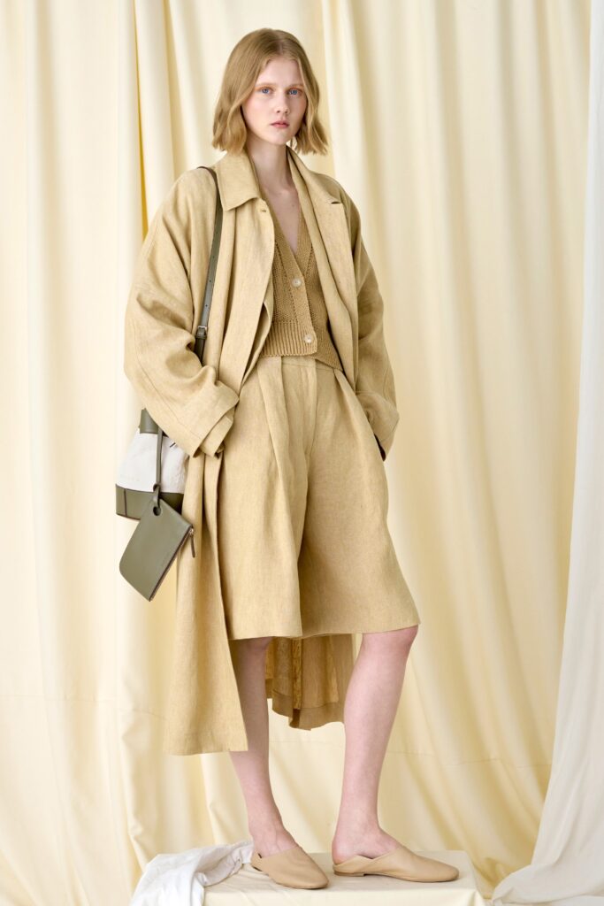 A relaxed beige cotton coat paired with wide-leg shorts and a collared top.