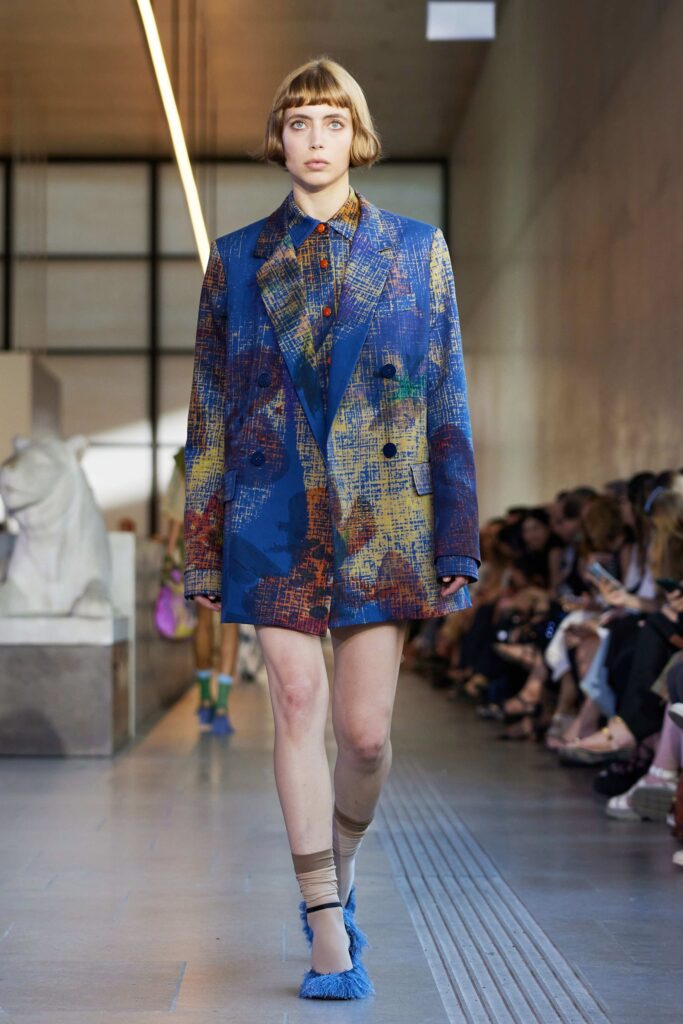 An oversized multicolor blazer paired with shorts, featuring a bold artistic print.