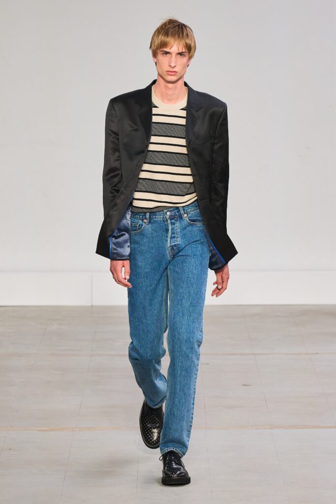 A fitted black jacket paired with striped shirt and blue straight-leg pants.