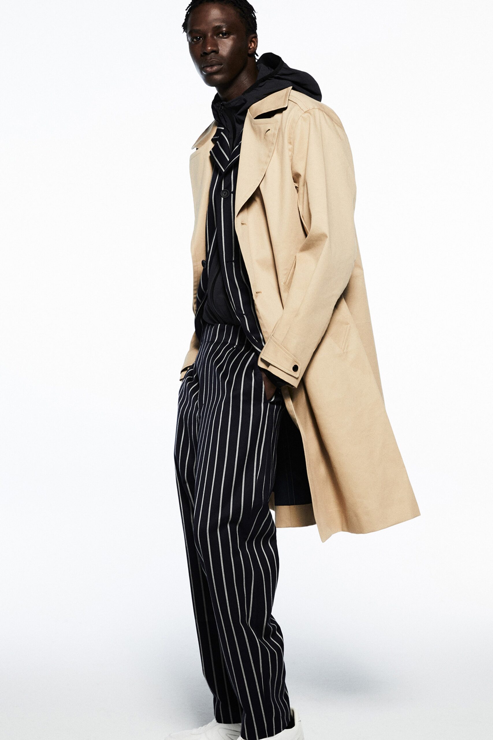 A relaxed beige coat paired with black striped pants featuring a collared design.