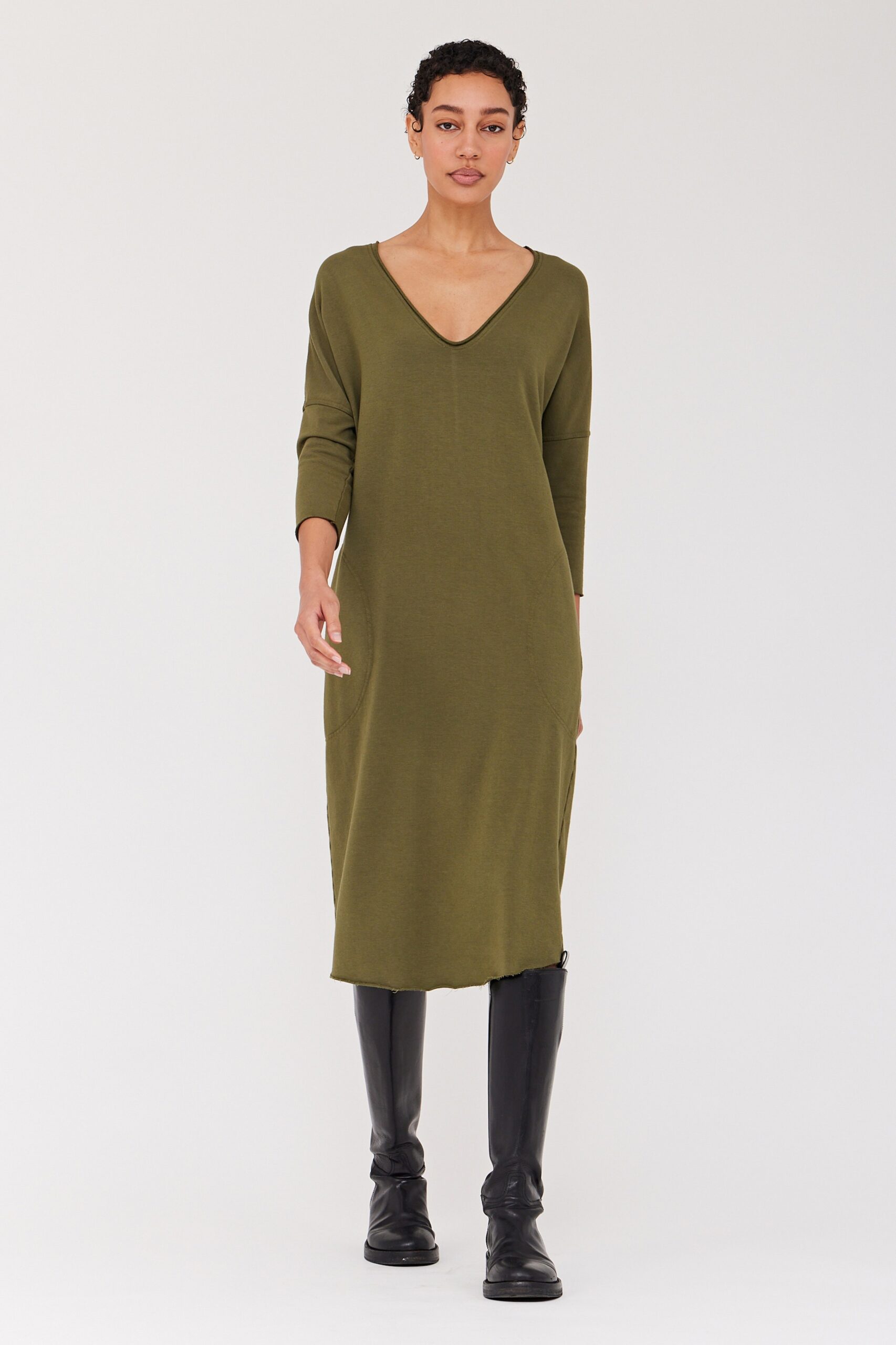 A relaxed green cotton dress with a V-neckline and long sleeves.