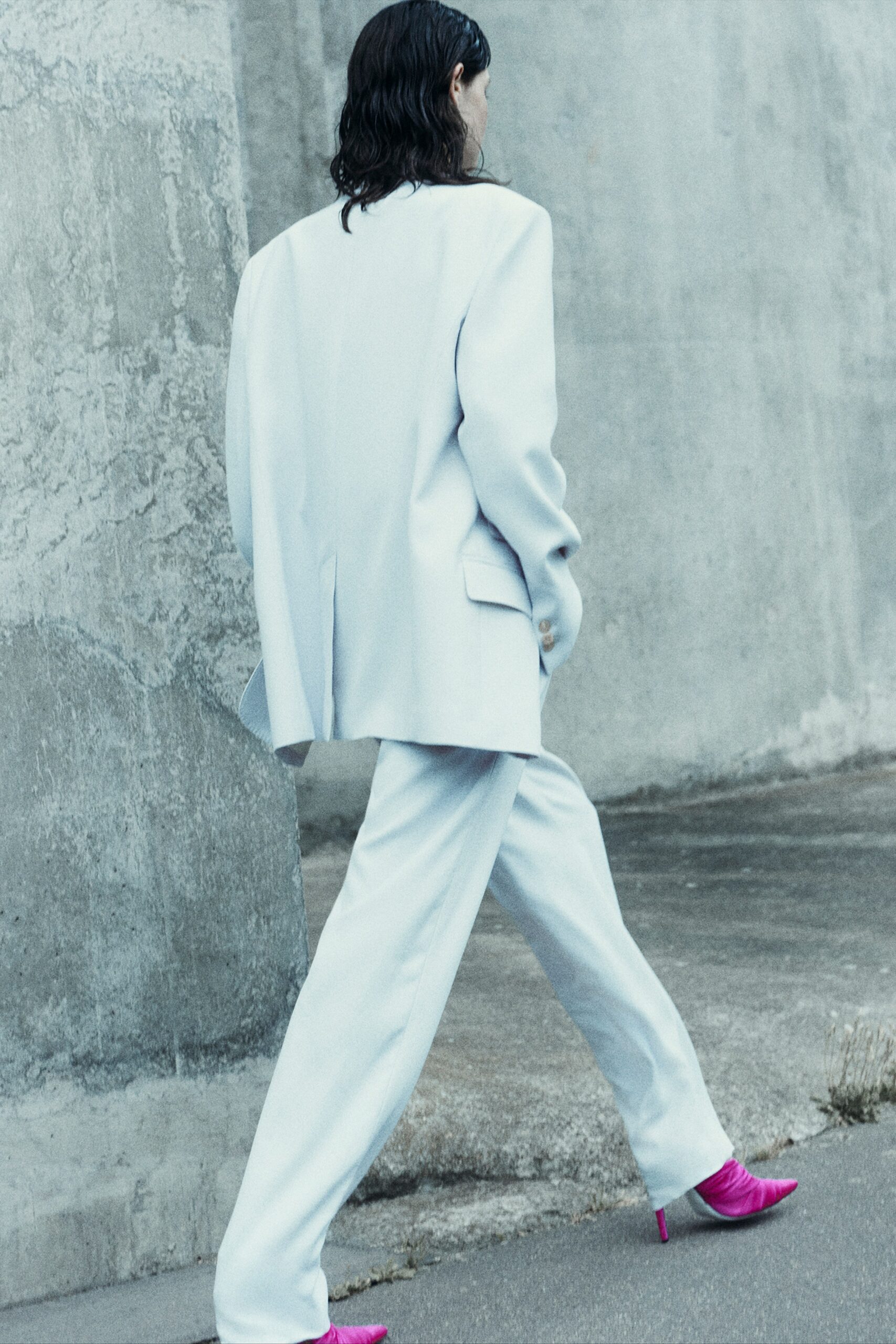 A relaxed white suit with long sleeves and a collared design, featuring straight-leg trousers.