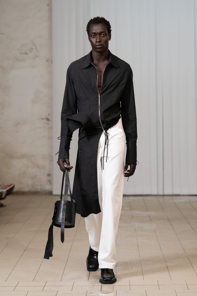 An asymmetric black long-sleeve shirt paired with white cotton pants for a modern look.