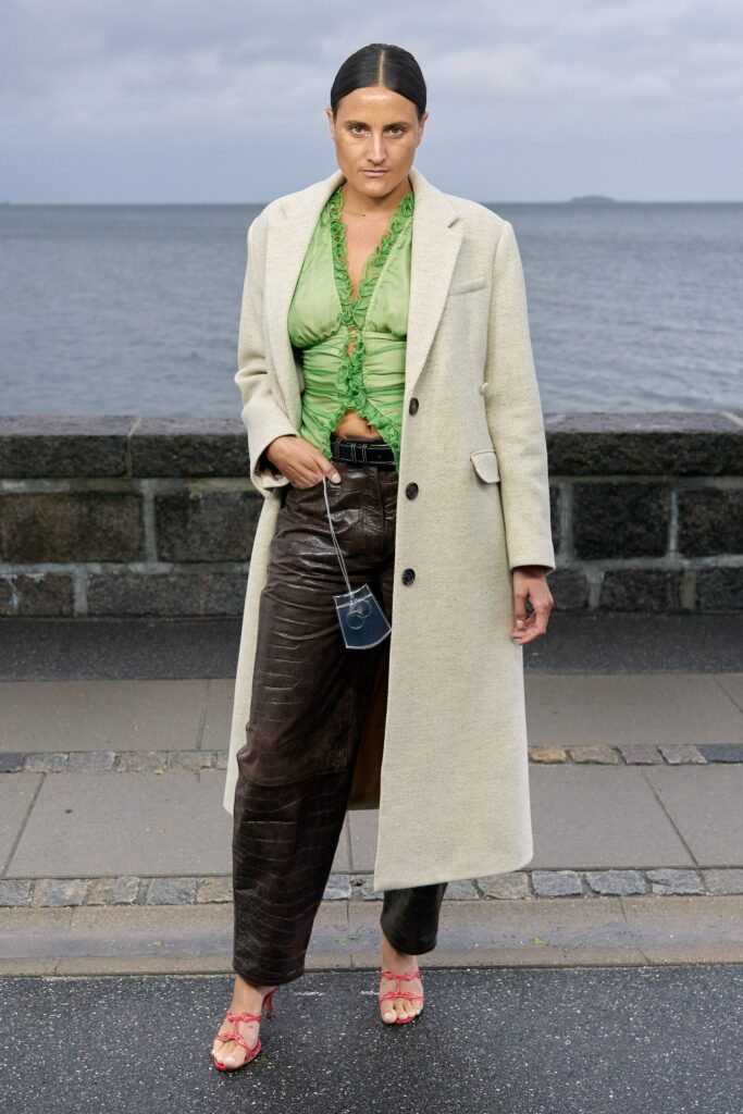 A fitted beige coat paired with brown leather pants, featuring a collared design and buttoned details.
