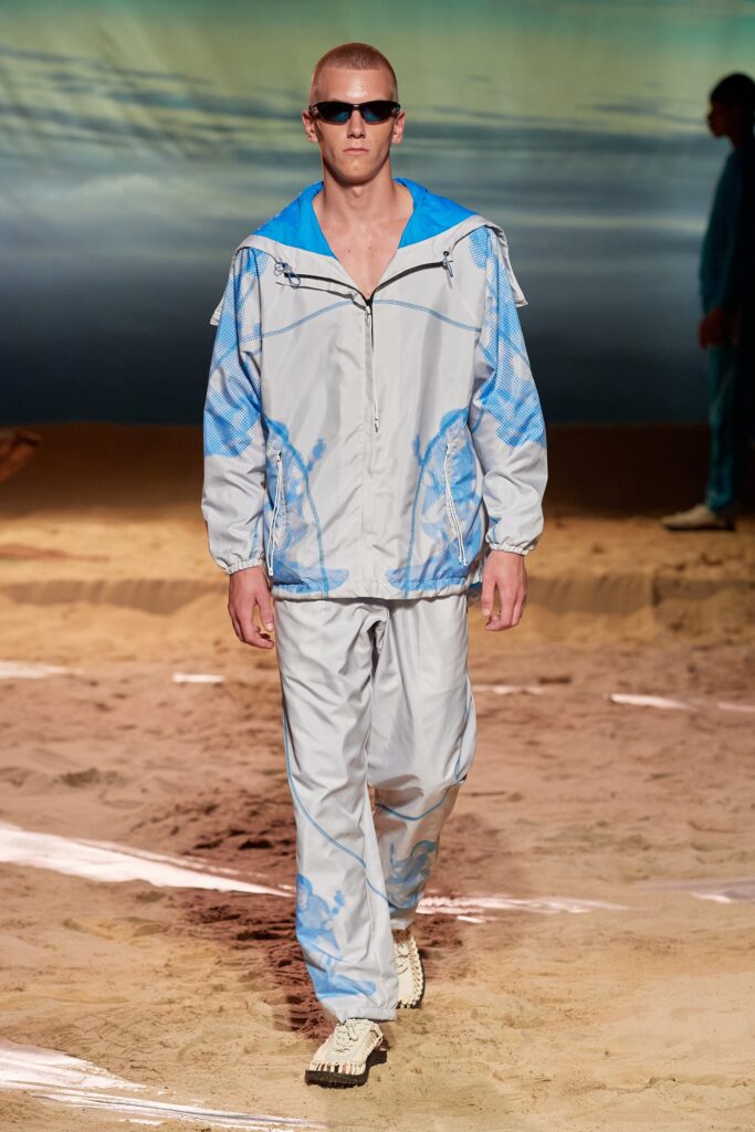 A relaxed-fit blue and gray printed jacket with matching pants, featuring a zippered front and long sleeves.