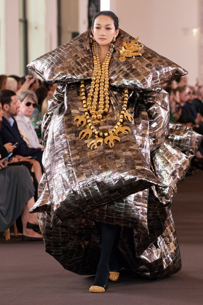 An oversized gold metallic dress with a high neckline and asymmetric design.