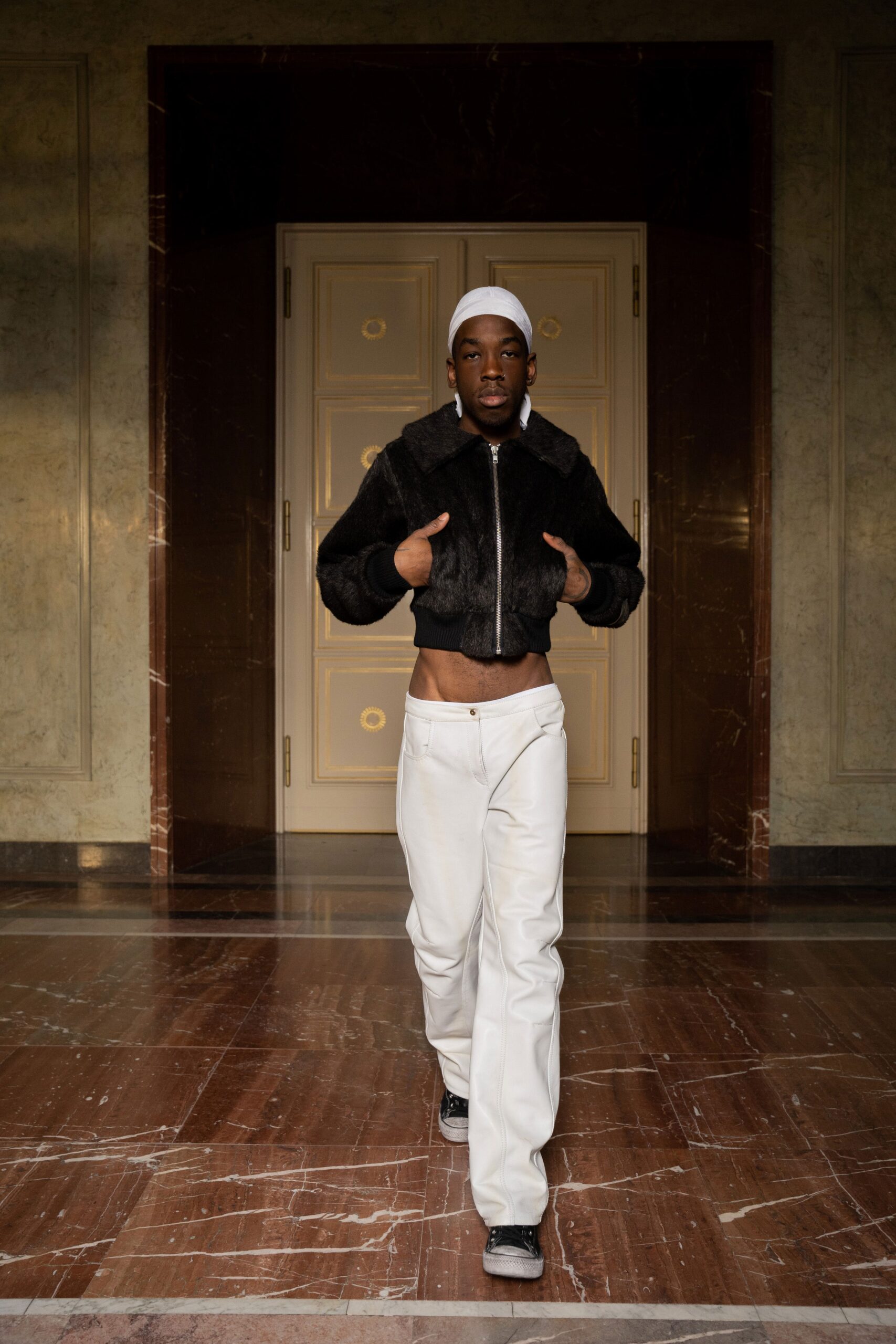 A fitted black leather jacket paired with white straight-leg pants, showcasing a modern street style.