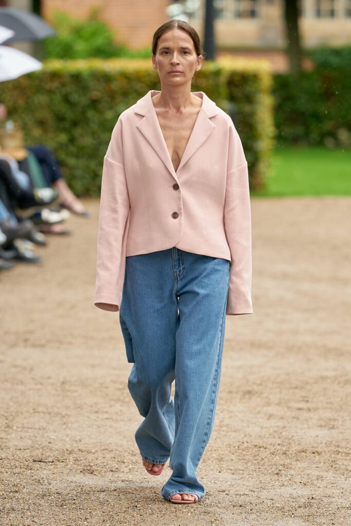 A relaxed pink cotton jacket paired with wide-leg blue pants, featuring a collared design and buttoned front.