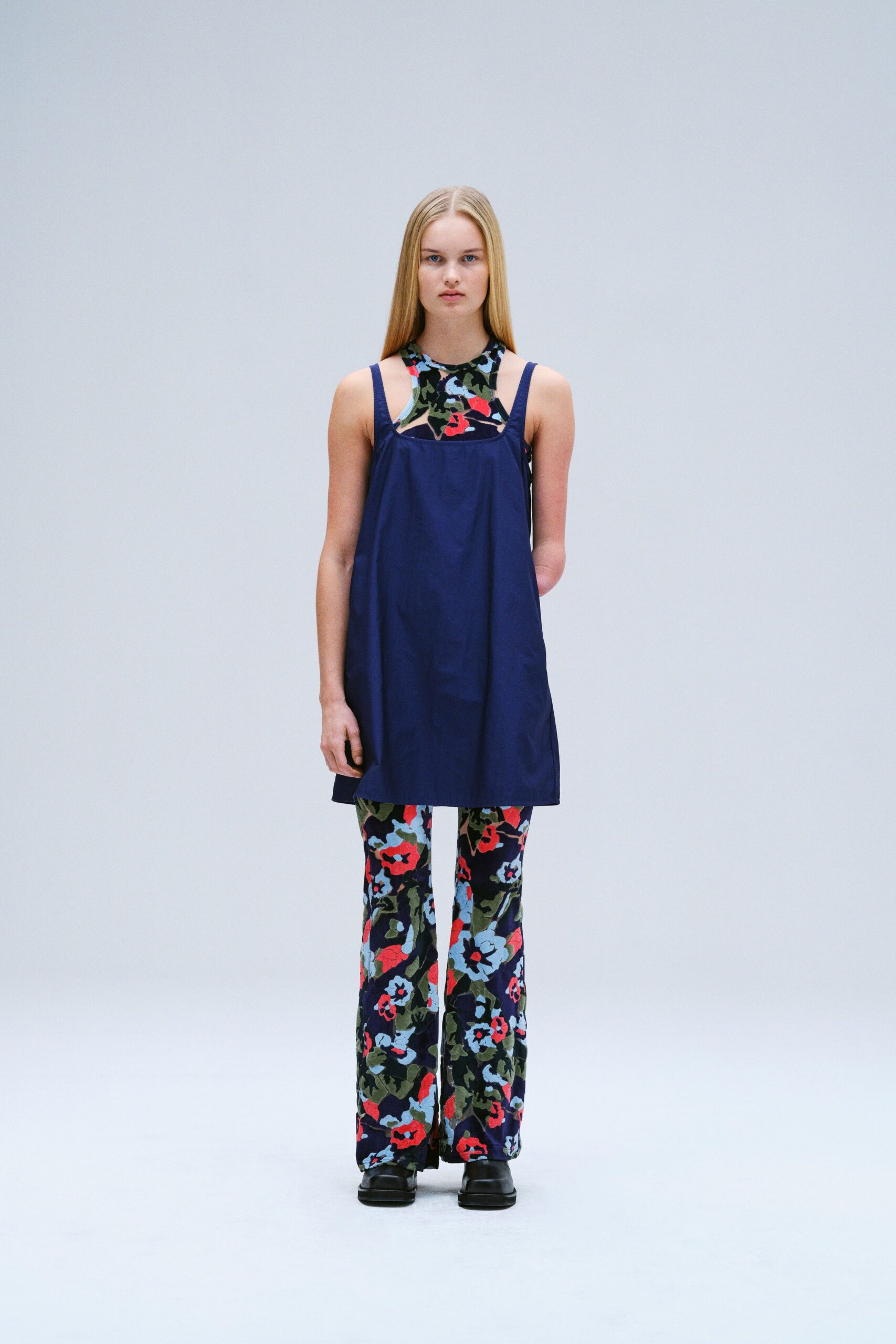 A relaxed blue sleeveless top paired with multicolor floral flared pants.