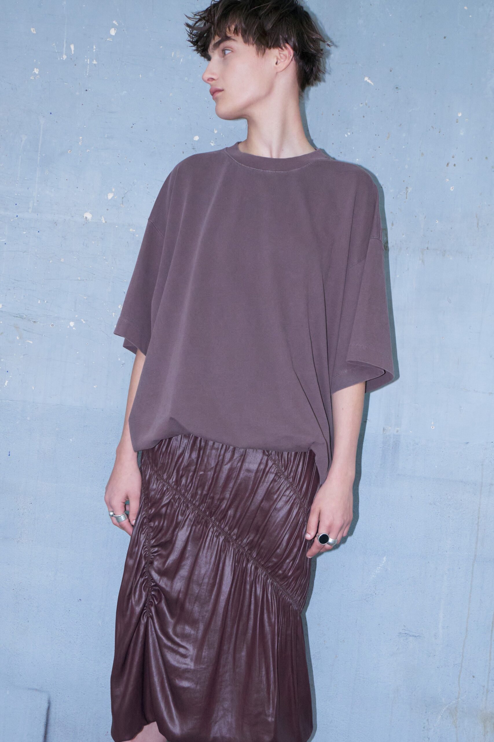 A relaxed brown cotton top paired with a high-waisted ruched leather skirt.