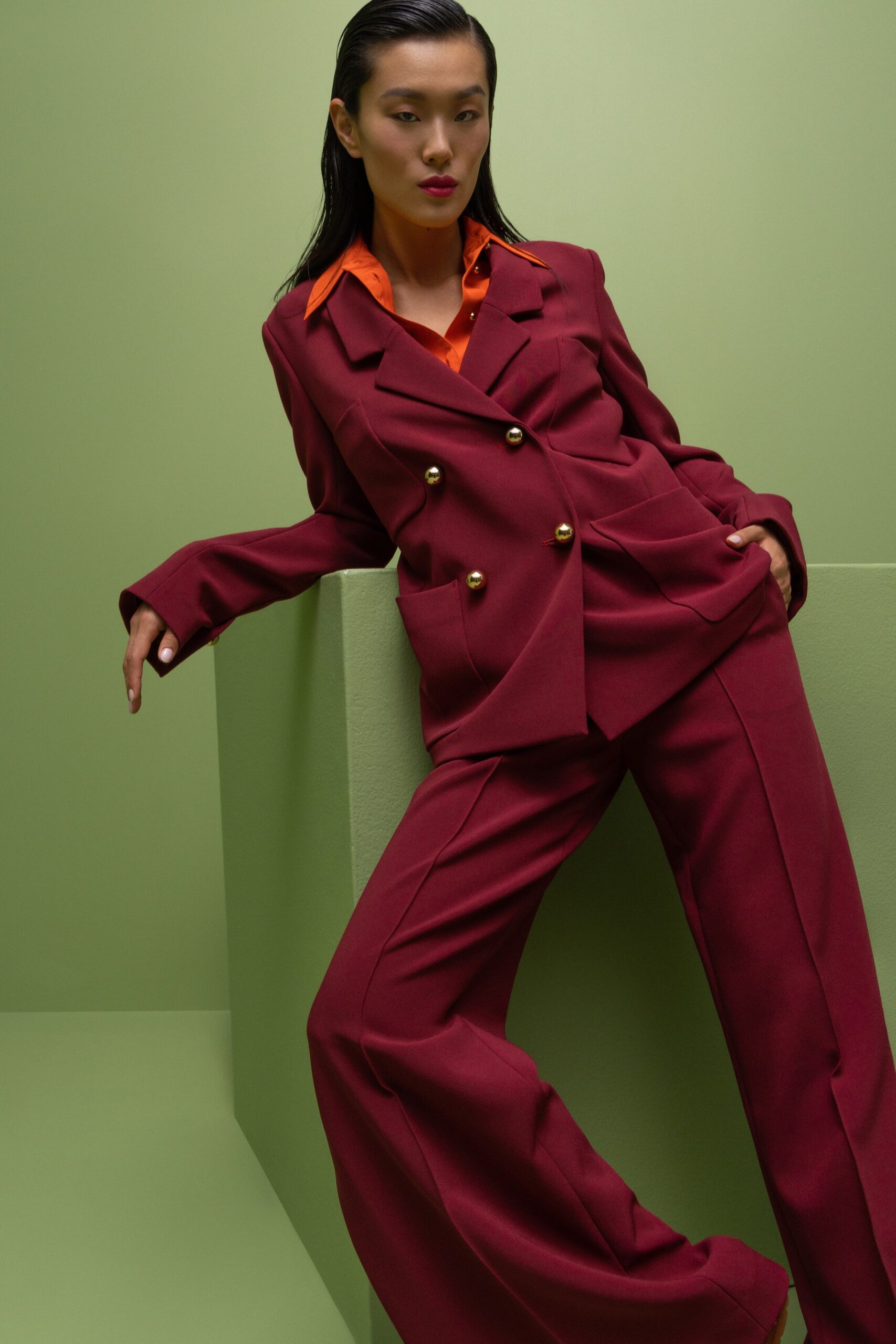 A tailored burgundy suit with long sleeves, a collared shirt, and wide-leg trousers.
