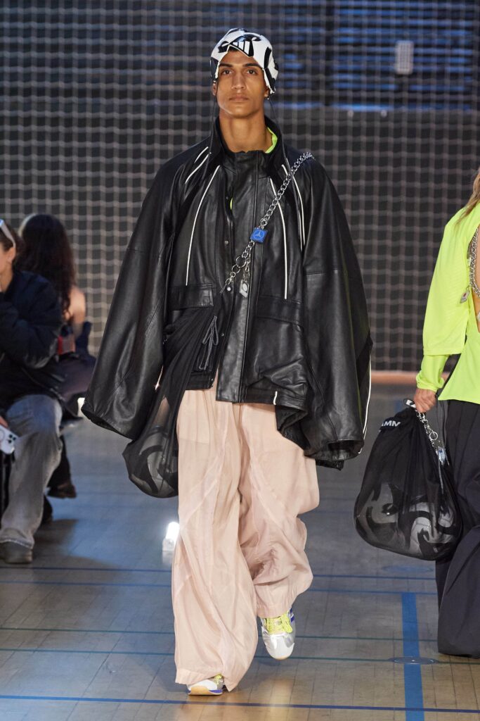 An oversized black leather jacket paired with relaxed pink cotton pants.