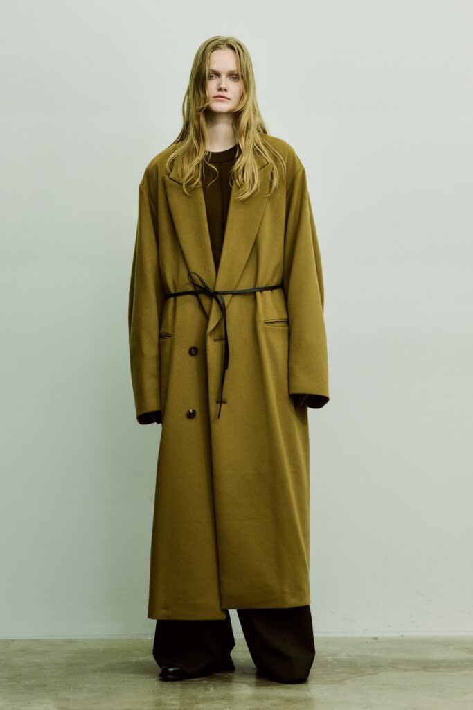 An oversized brown wool coat with a belted waist and wide-leg pants.