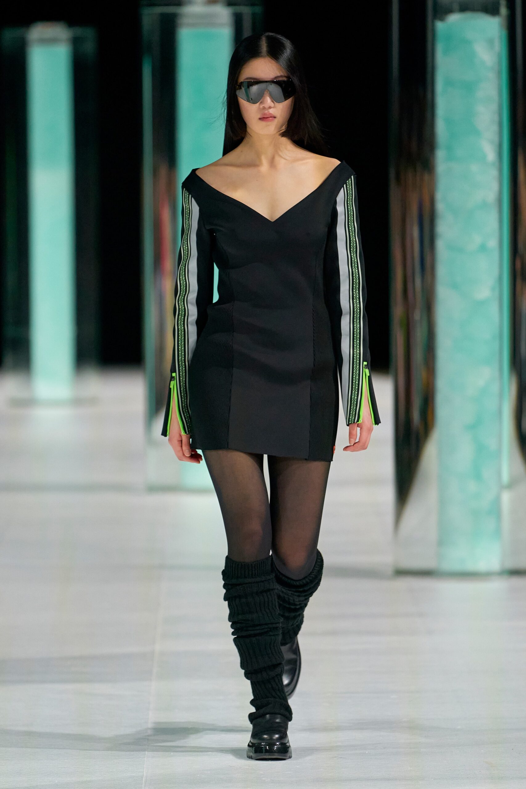 A fitted black dress with long sleeves, a V-neckline, and an asymmetric design.