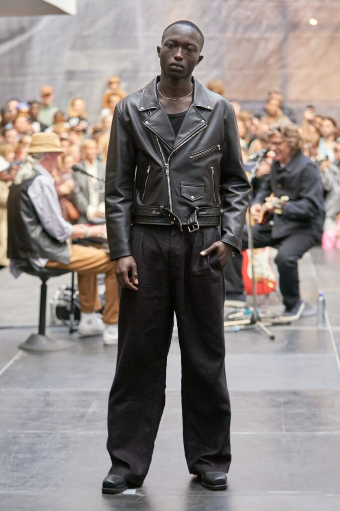 A relaxed black leather jacket with a collared design paired with wide-leg black pants.