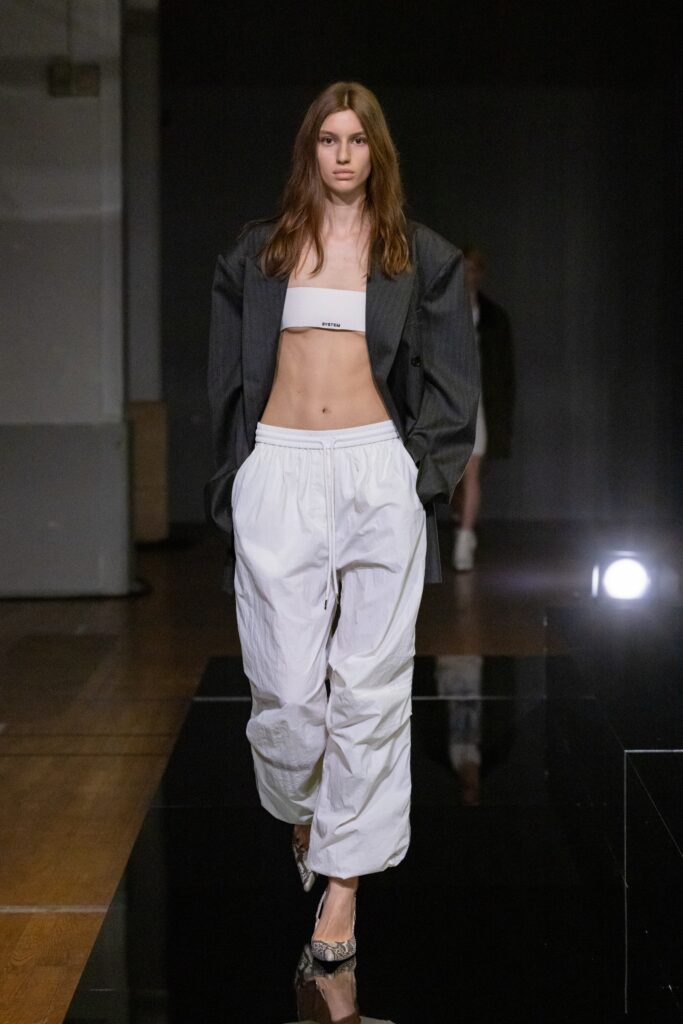 A relaxed black jacket paired with white pants featuring a zippered detail.