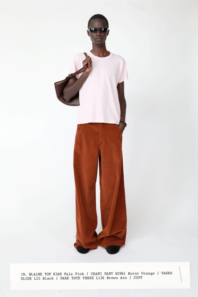 A relaxed pink cotton top paired with high-waisted wide-leg orange velvet pants.