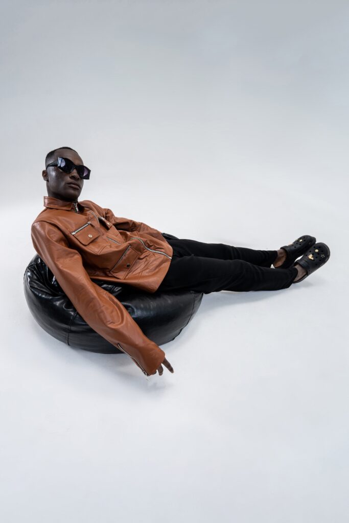 A fitted brown leather jacket with long sleeves paired with black fitted pants.