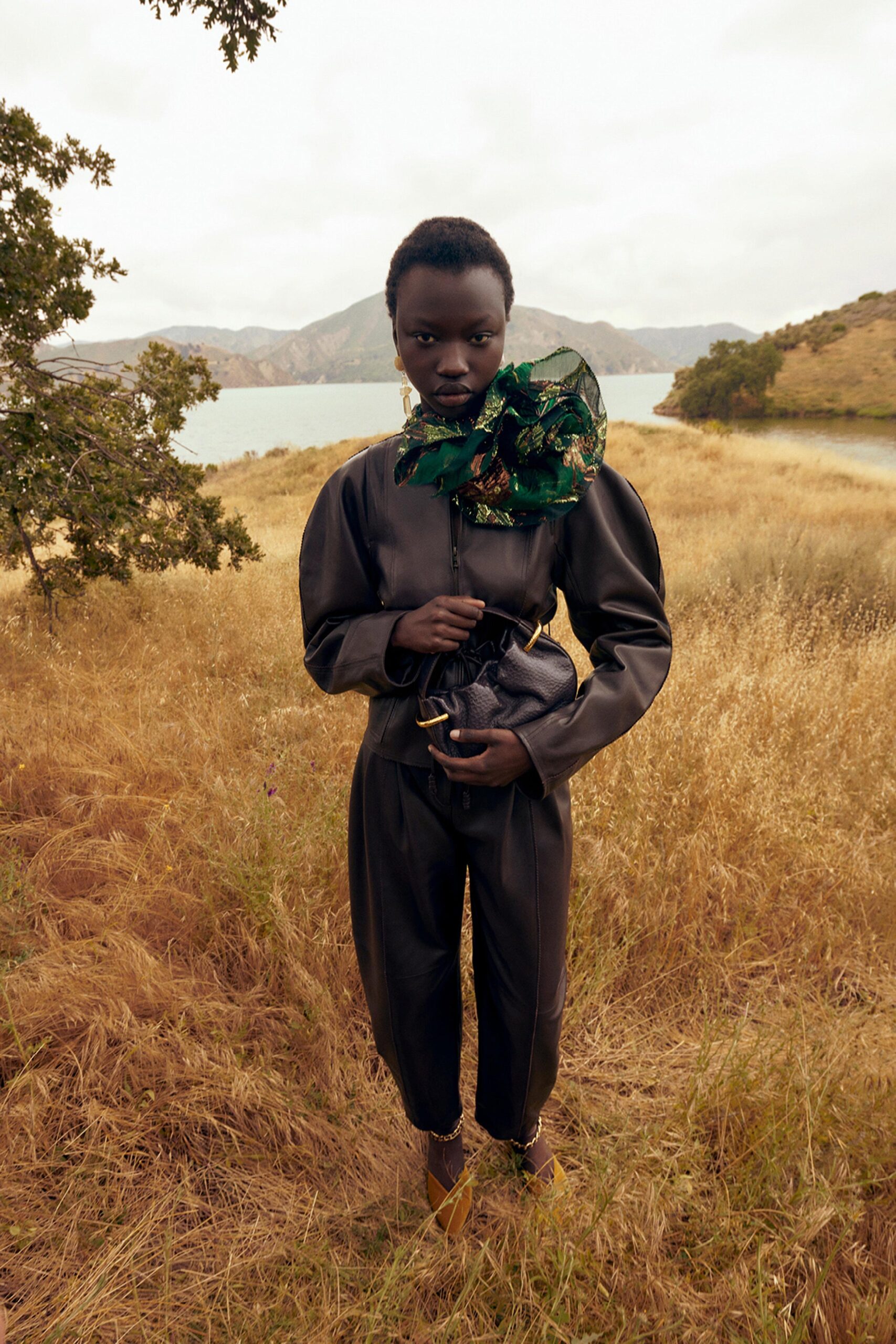 A fitted black leather jacket with long sleeves and a collared design, paired with matching pants.