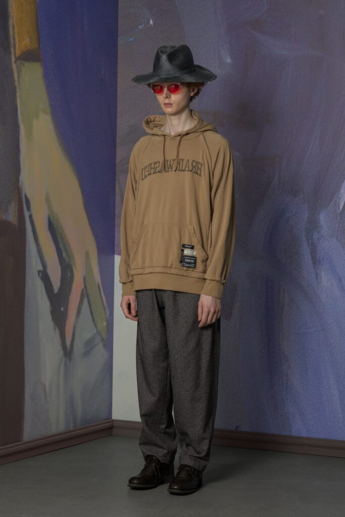 A relaxed brown hoodie with a hood and long sleeves paired with gray relaxed-fit pants.