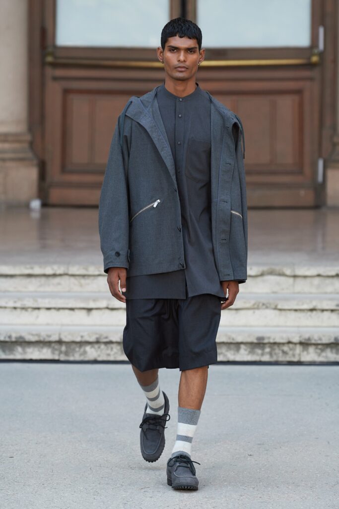 A relaxed-fit gray jacket layered over a black collared shirt with long sleeves.