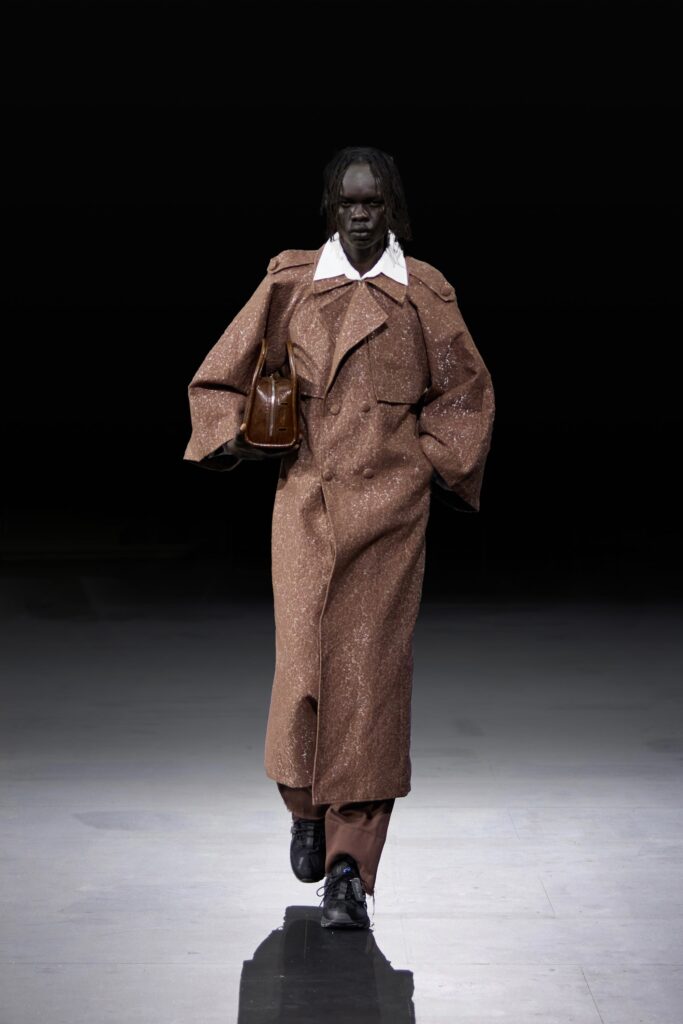 An oversized brown wool coat with a buttoned front and dramatic sleeves.