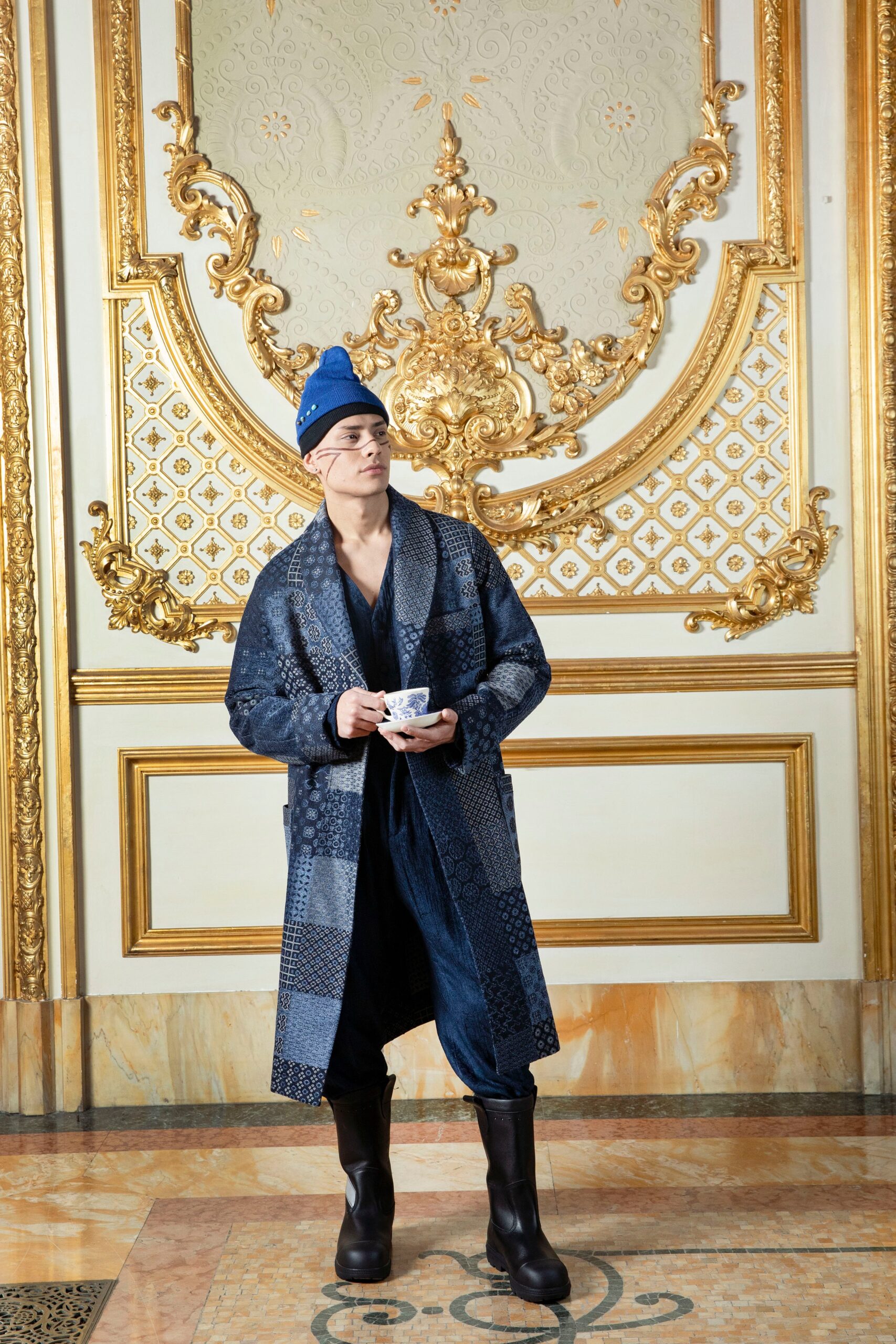 A relaxed blue cotton coat with long sleeves and a collared design, featuring layered details.