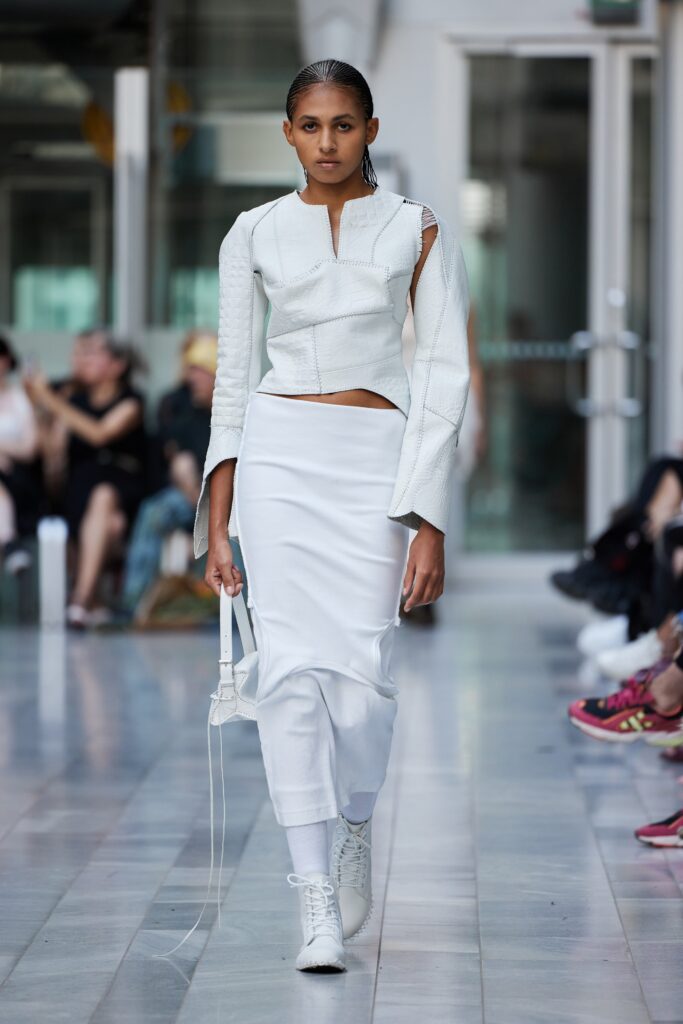 A fitted white leather long-sleeve top paired with a sleek white skirt for a modern look.